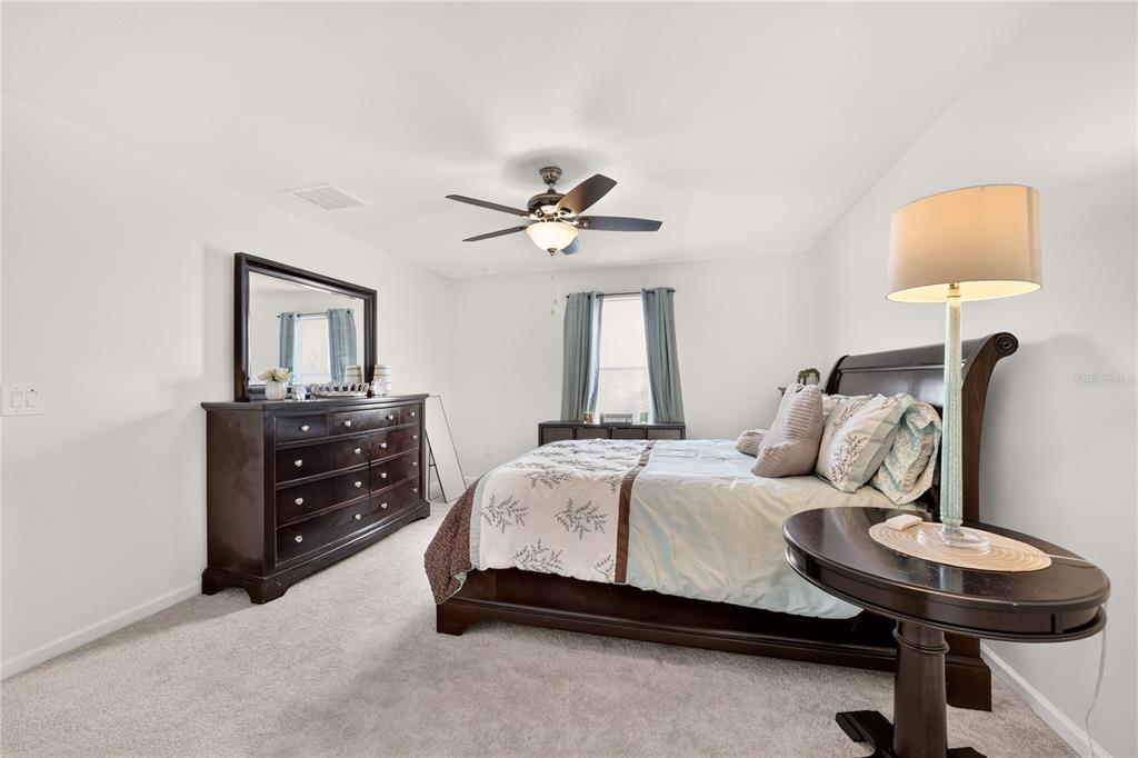 A bedroom features a dark wood bed frame, matching dresser with mirror, and a ceiling fan — 4745 SW 83RD LOOP, OCALA, FL