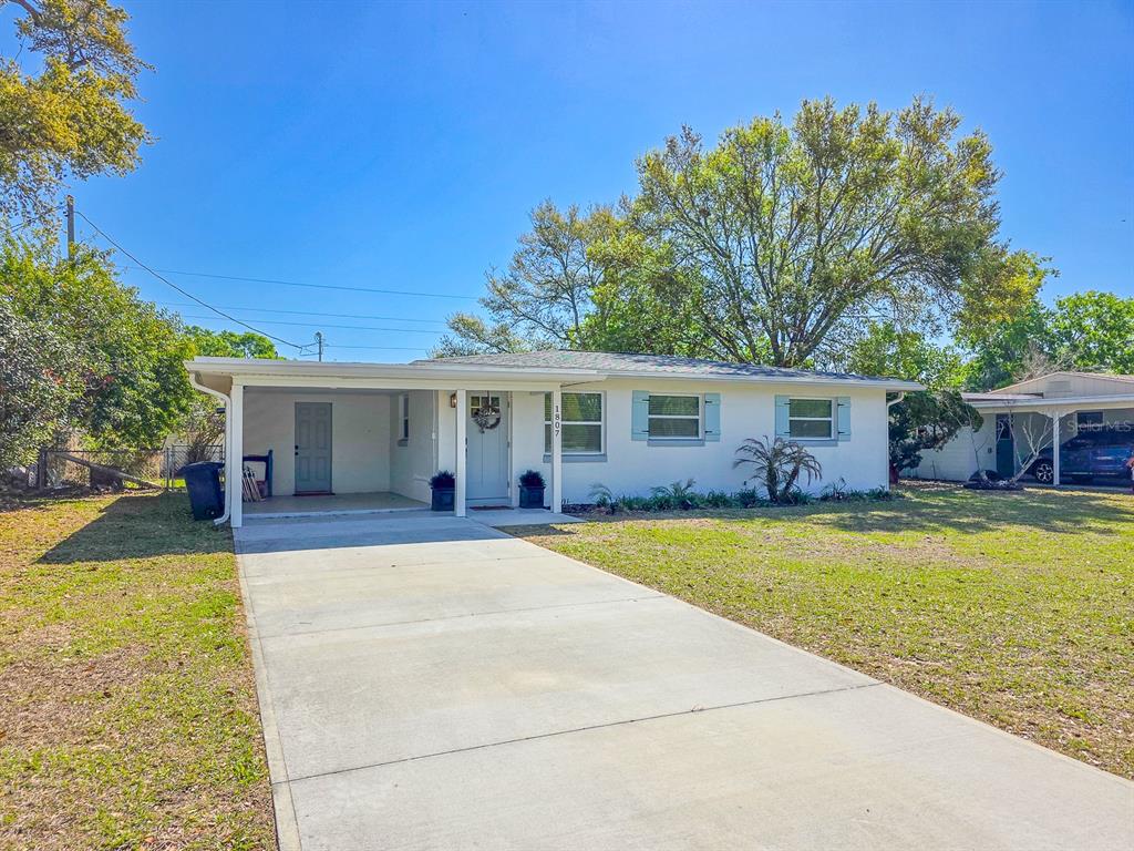 A single-story white house with a carport and light blue shutters sits on a lawn — 1807 GOLFVIEW BOULEVARD, SOUTH DAYTONA, FL