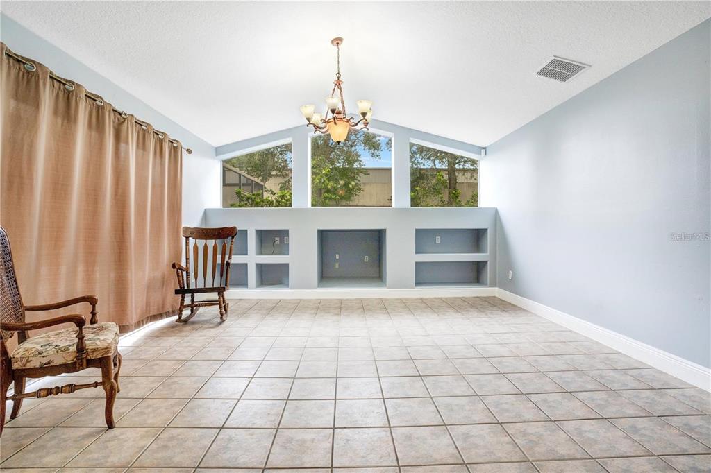 A sunroom with tile flooring, a vaulted ceiling, a chandelier, and built-in wall shelving — 14203 VISTA DEL LAGO BOULEVARD, CLERMONT, FL