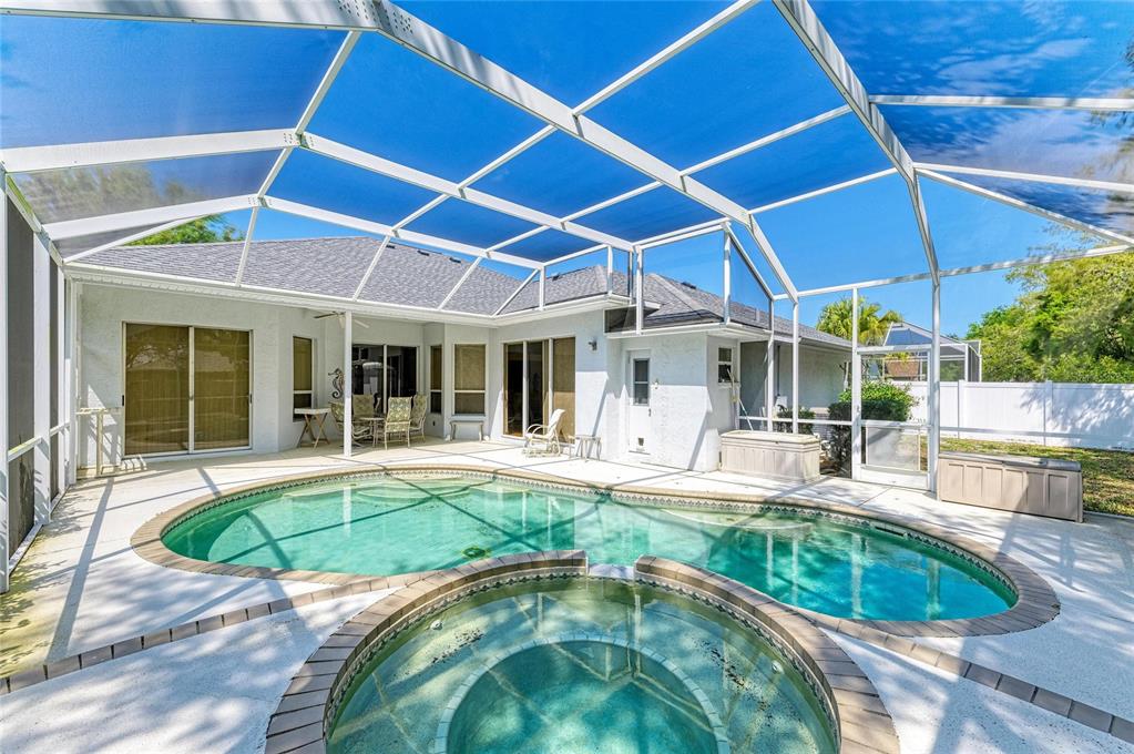 A backyard swimming pool and spa are enclosed by a screened lanai behind a house — 7604 52ND TERRACE E, BRADENTON, FL