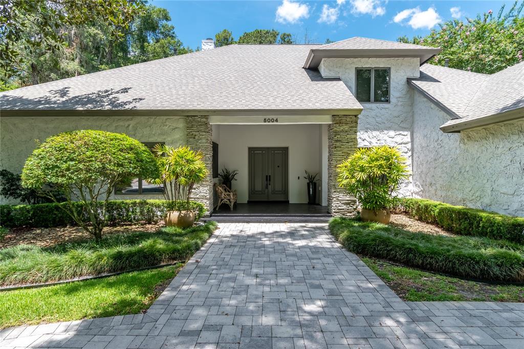 A stone-textured house exterior features a paved walkway leading to a double-door entryway — 5004 SE 5TH AVENUE, OCALA, FL