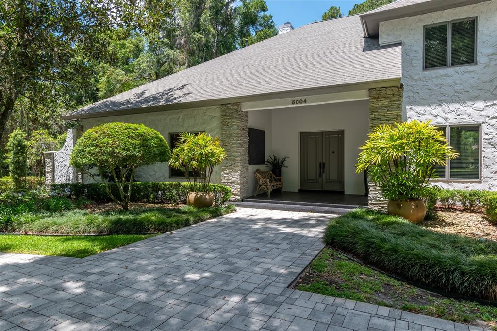 A paved walkway leads to the front entrance of a white house with stone accents — 5004 SE 5TH AVENUE, OCALA, FL