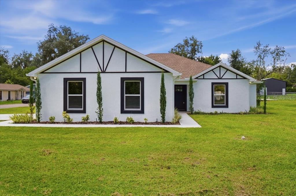 A white single-story house with black trim and a gabled roof sits on a lawn — 829 N CLERMONT AVENUE, FORT MEADE, FL