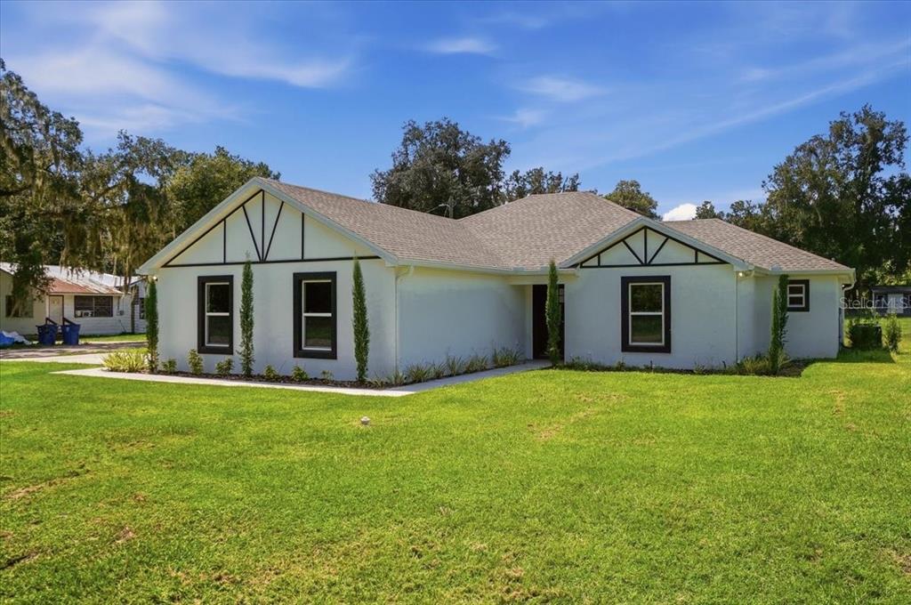 A single-story white house with dark-trimmed windows and a gabled roof sits on a lawn — 829 N CLERMONT AVENUE, FORT MEADE, FL
