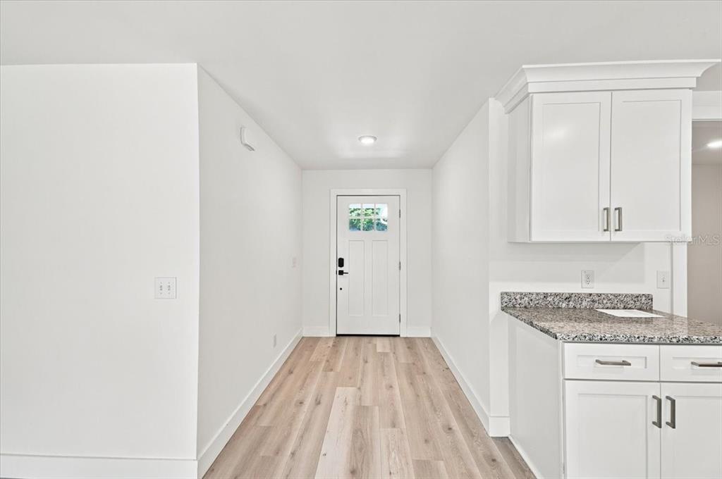 A bright entryway features light wood-look flooring, white walls, and a white front door — 829 N CLERMONT AVENUE, FORT MEADE, FL