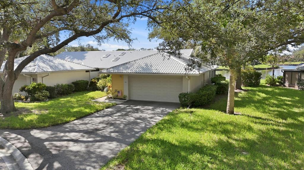 A single-story house with a white tile roof, a two-car garage, and a paved driveway — 214 SOUTHAMPTON DRIVE UNIT 327, VENICE, FL