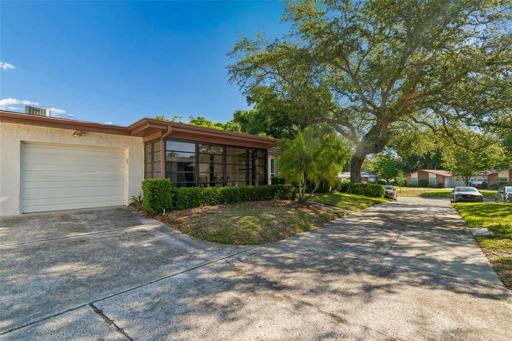 A single-story house with a white garage, a screened-in porch, and a large oak tree — 2150 SHELLY DRIVE UNIT B, PALM HARBOR, FL