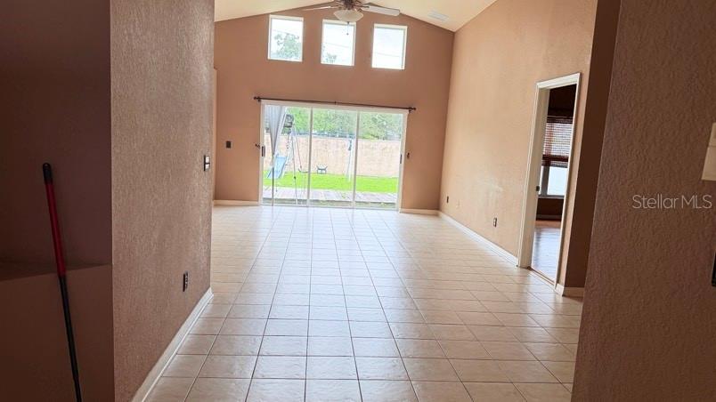 An open living room features light-colored tile flooring, vaulted ceilings, and sliding glass patio doors — 1120 VINETREE DRIVE, BRANDON, FL