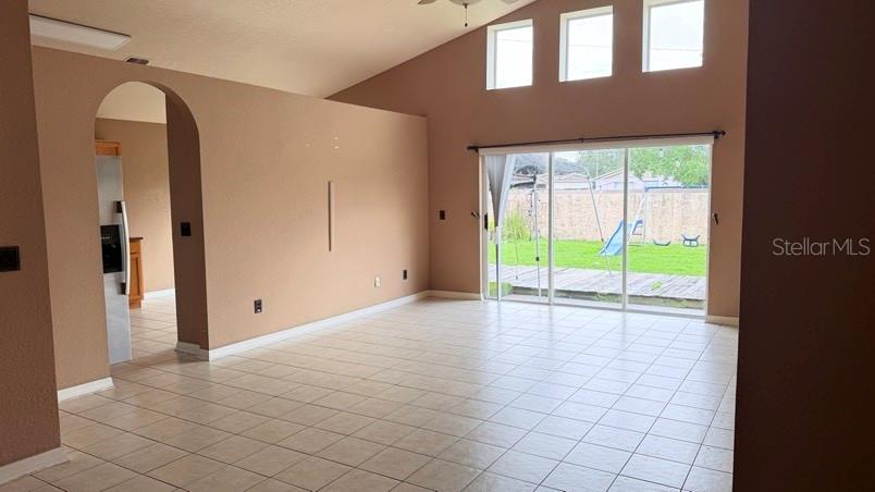 A living room with tile floors, vaulted ceilings, and sliding glass doors leading to a yard — 1120 VINETREE DRIVE, BRANDON, FL