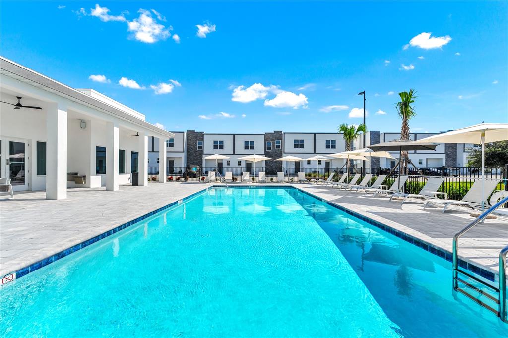 A rectangular swimming pool sits on a patio in front of modern townhome buildings — 277 FAMAGUSTA DRIVE, DAVENPORT, FL