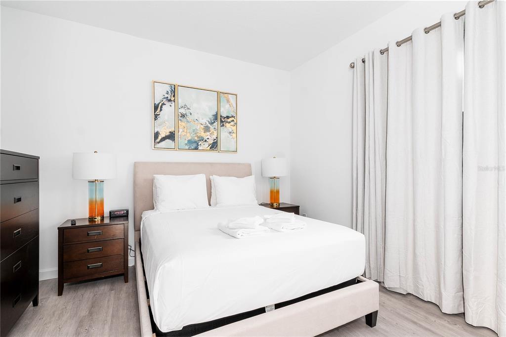 A bedroom features a bed with white linens, two nightstands with lamps, and floor-length curtains — 277 FAMAGUSTA DRIVE, DAVENPORT, FL