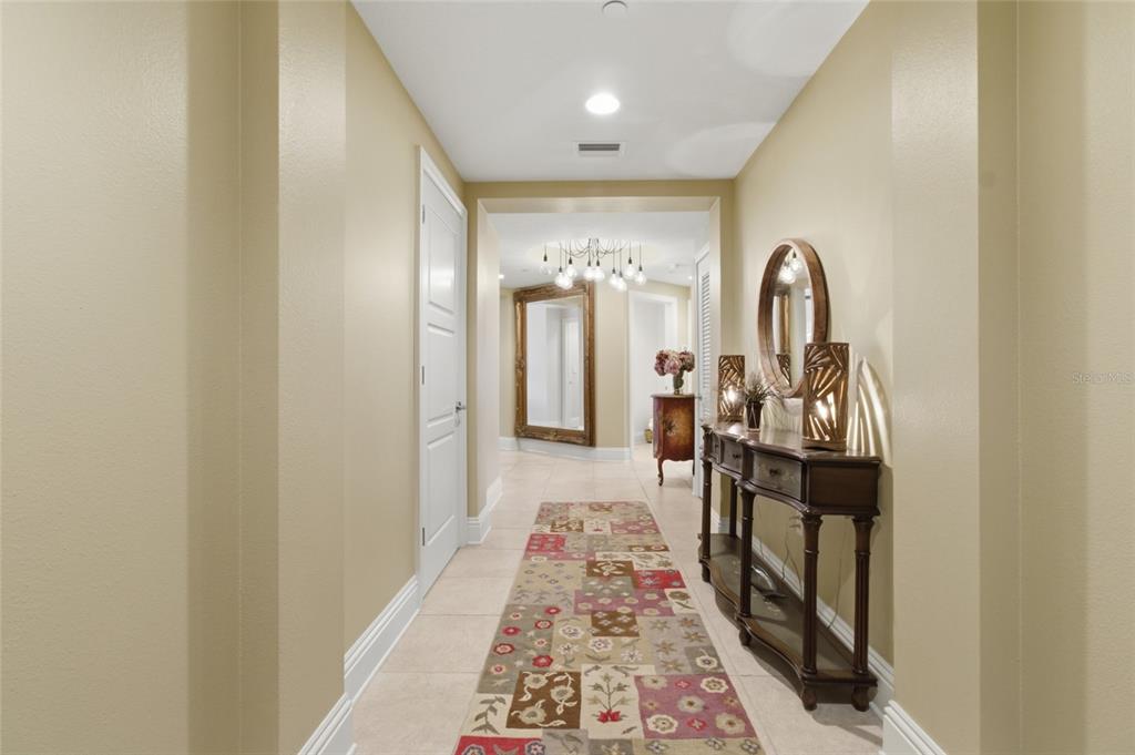 A foyer features a large gold-framed mirror, a floral chest, and a modern light fixture — 11 BAYMONT STREET UNIT 608, CLEARWATER BEACH, FL