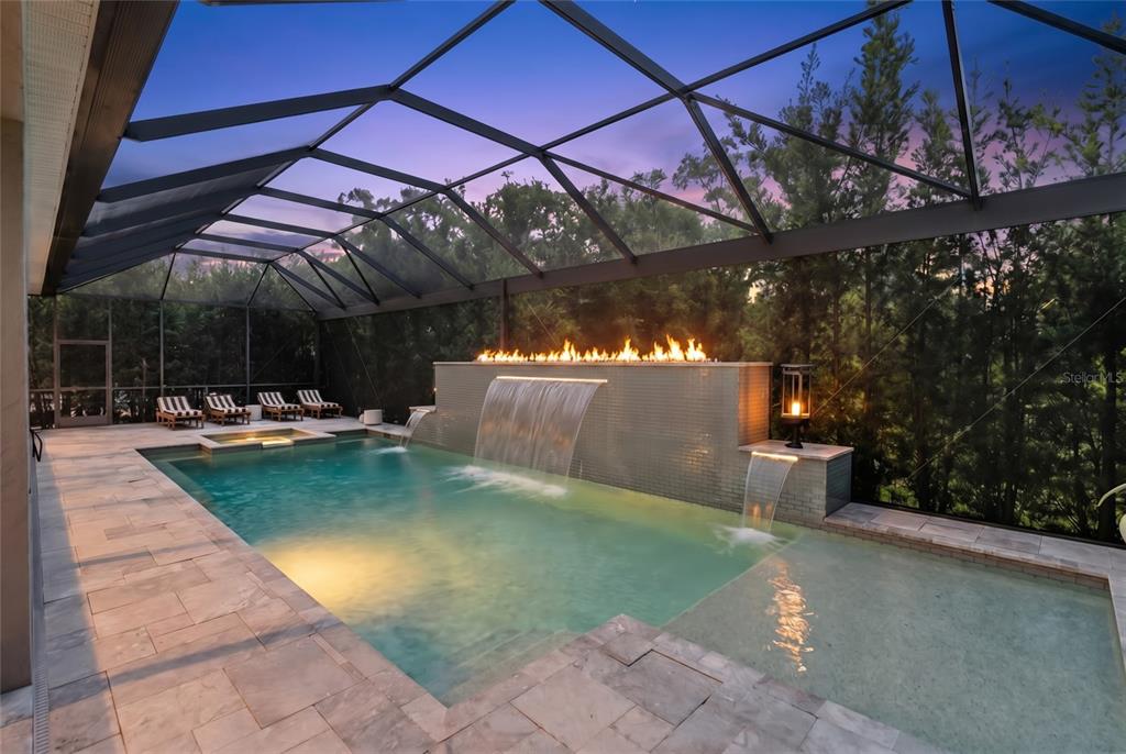 A screened-in pool area features a fire feature, multiple waterfalls, and stone patio flooring — 12215 PORTSMOUTH TERRACE, BRADENTON, FL