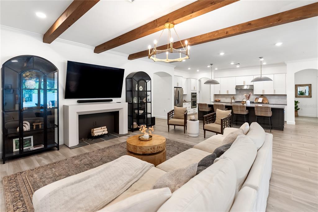 A living room with wood ceiling beams, a fireplace, and an open kitchen — 12215 PORTSMOUTH TERRACE, BRADENTON, FL