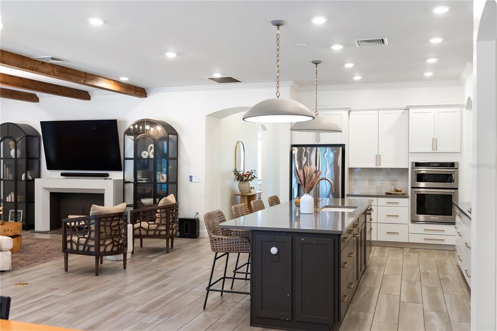 A modern open-concept kitchen features a dark island, white cabinetry, and wood-look tile flooring — 12215 PORTSMOUTH TERRACE, BRADENTON, FL