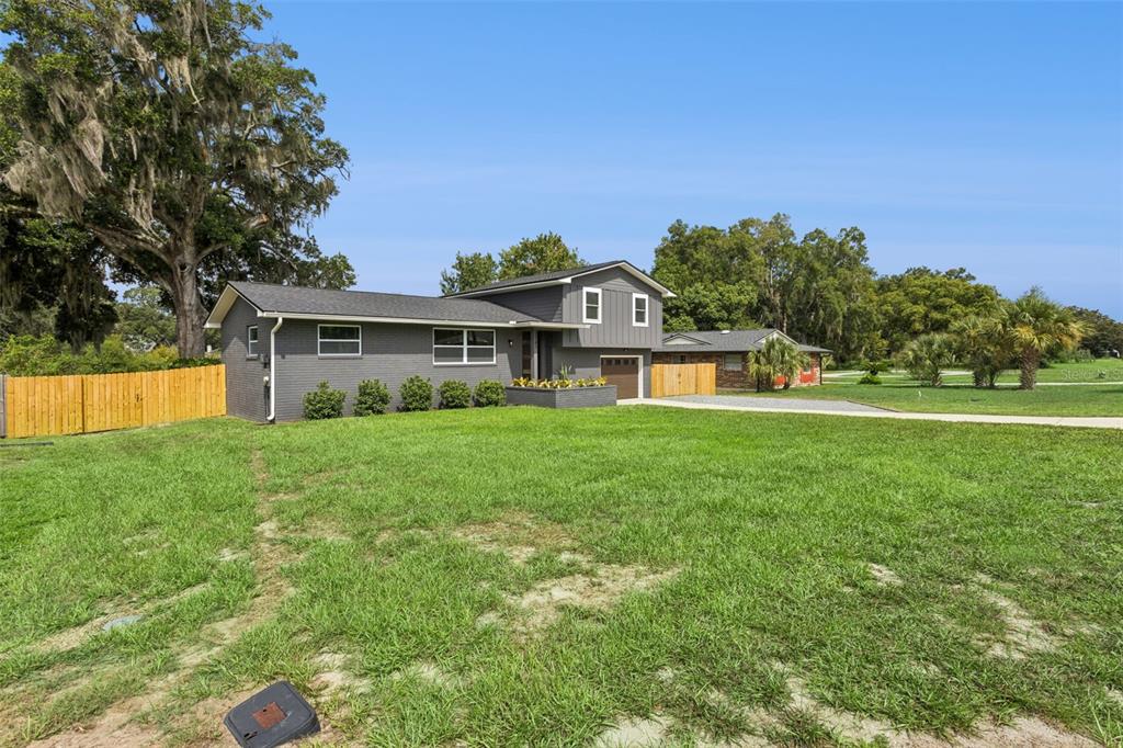 A gray, two-story house with a brick exterior, a wooden fence, and a large lawn — 33241 FAIRWAY ROAD, LEESBURG, FL
