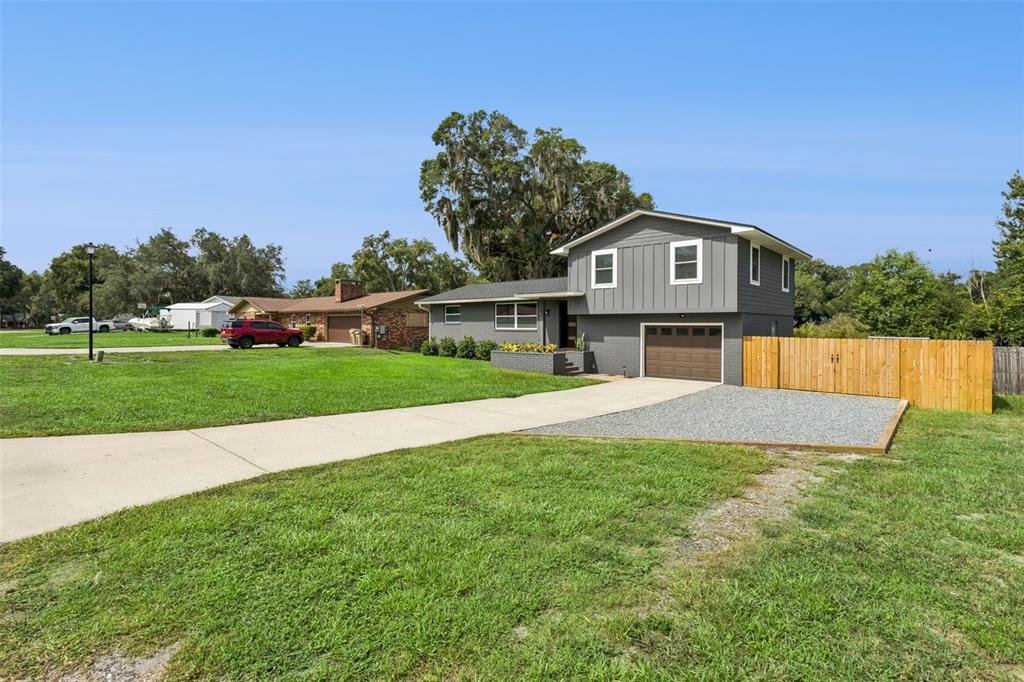 A two-story gray house with a brown garage door and a wooden fence — 33241 FAIRWAY ROAD, LEESBURG, FL