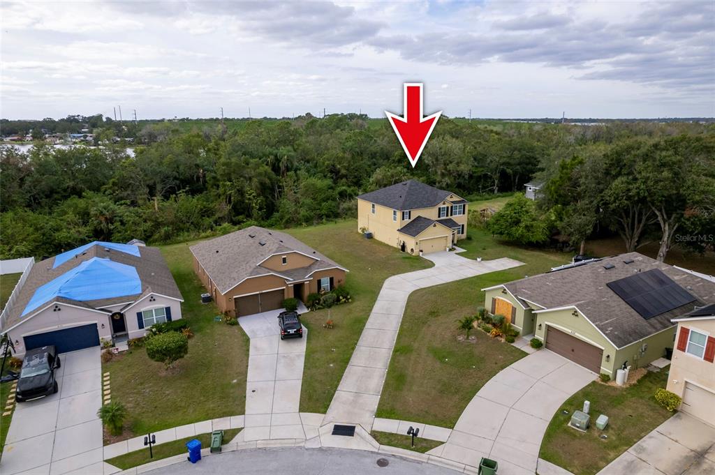 An aerial view shows a two-story yellow house with a red arrow pointing toward it — 4162 ROBERTA DRIVE, WINTER HAVEN, FL