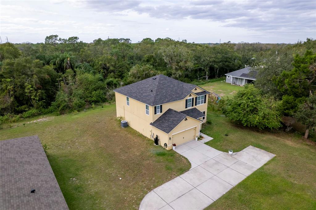 An aerial view shows a two-story yellow house with a dark roof and concrete driveway — 4162 ROBERTA DRIVE, WINTER HAVEN, FL