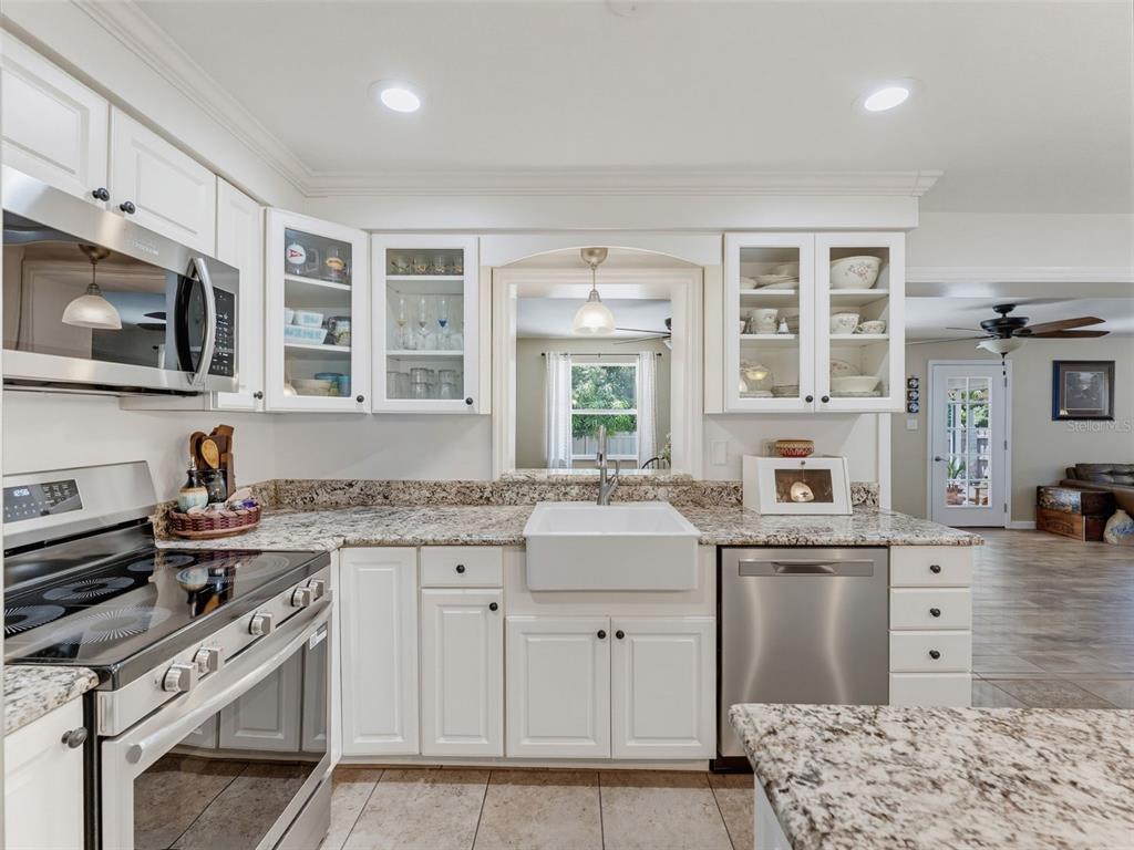 A kitchen with white cabinets, granite countertops, a farmhouse sink, and stainless steel appliances — 1575 JASMINE WAY, CLEARWATER, FL