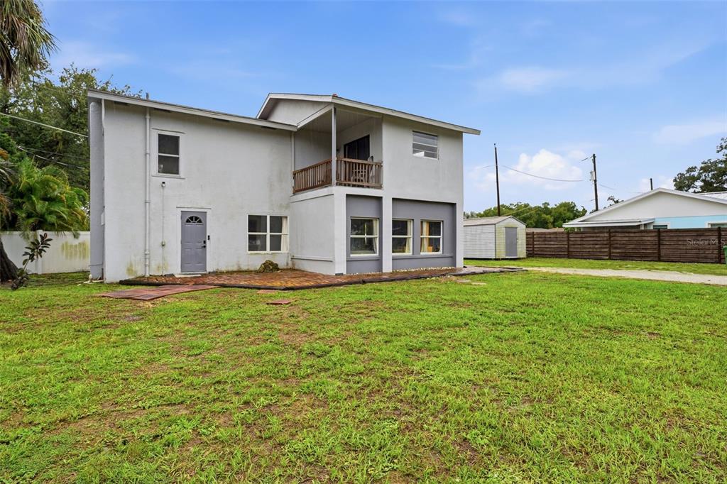 The exterior of a two-story house with a gray door, balcony, and a brick patio — 3052 ALTA VISTA ST, SARASOTA, FL