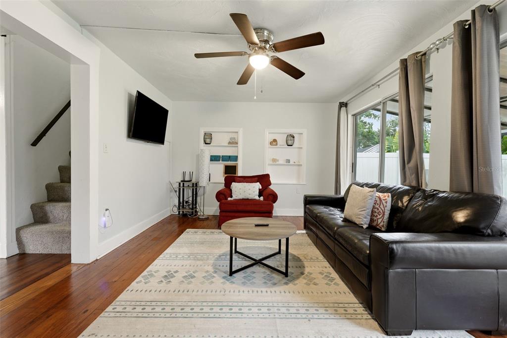 A living room features a dark leather sofa, a red armchair, and a circular coffee table — 3052 ALTA VISTA ST, SARASOTA, FL