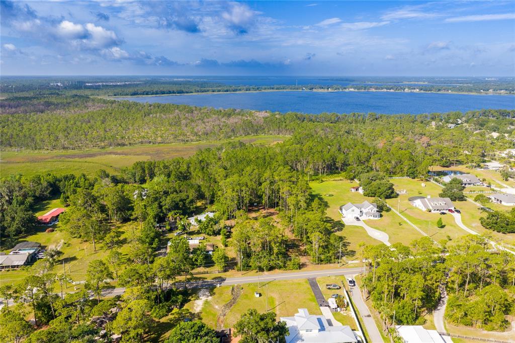 An aerial view shows houses scattered among trees and grassy fields near a large lake — BASS HIGHWAY, ST CLOUD, FL