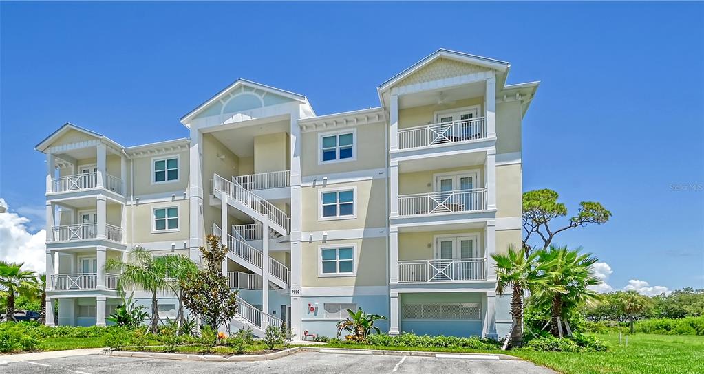 A three-story apartment building with exterior staircases, balconies, and a parking lot in front — 7930 34TH AVENUE W UNIT 102, BRADENTON, FL