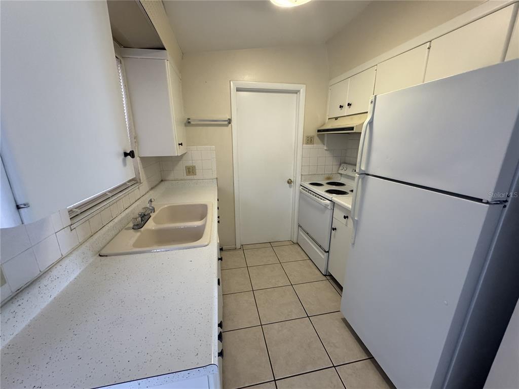 A galley kitchen features white cabinets, a double sink, a white stove, and a refrigerator — 376 BRIARWOOD ROAD, VENICE, FL