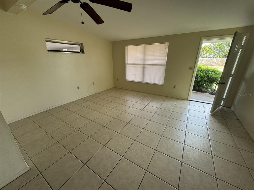 An empty room features light-colored tile flooring, a ceiling fan, and a door leading outside — 376 BRIARWOOD ROAD, VENICE, FL