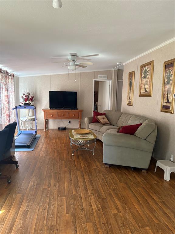 A living room features wood-look flooring, a beige sofa, a television on a wooden console — 10342 SHADY DRIVE, HUDSON, FL