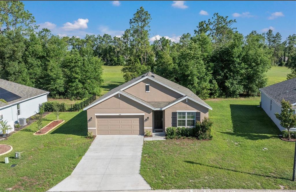 An aerial view of a single-story tan house with a two-car garage and green lawn — 160 HICKORY COURSE LOOP, OCALA, FL