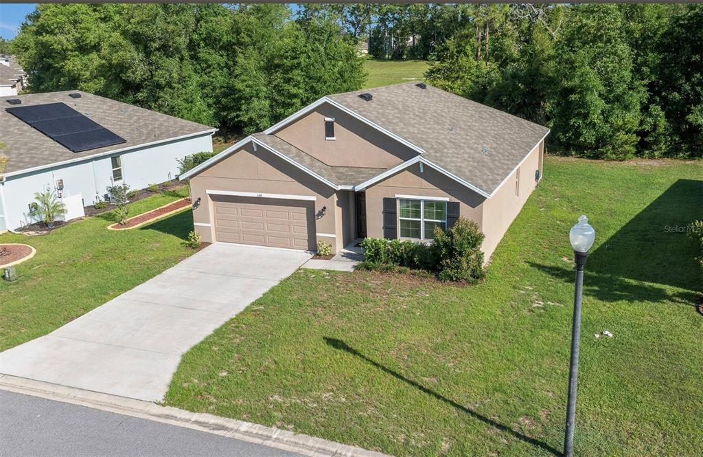 An aerial view of a single-story tan house with a two-car garage and shingled roof — 160 HICKORY COURSE LOOP, OCALA, FL