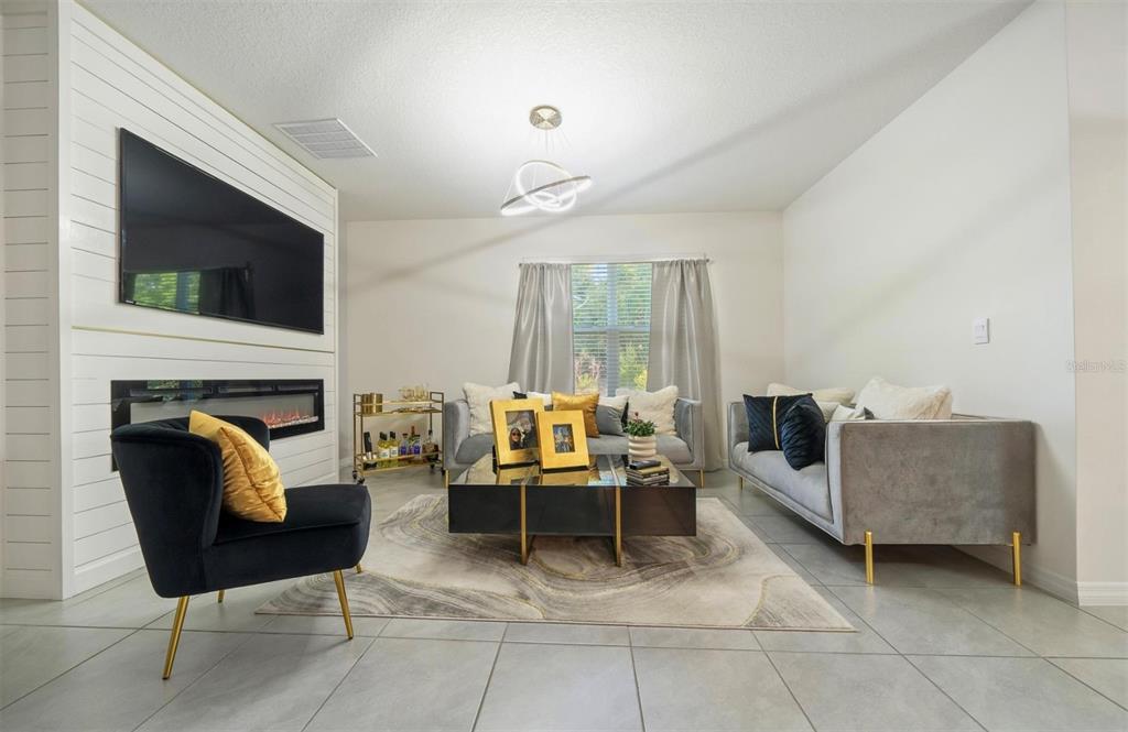 A modern living room features a shiplap fireplace wall, gray sofas, and a black armchair — 160 HICKORY COURSE LOOP, OCALA, FL