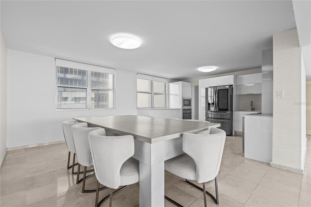 A dining area with a large table and chairs sits adjacent to a modern kitchen — #6 MARIANO RAMÍREZ BAGES UNIT 1, SAN JUAN, PR