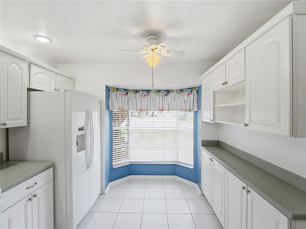 A white kitchen features gray countertops, white cabinetry, and white appliances on a tiled floor — 914 MICHIGAN AVENUE, ST CLOUD, FL