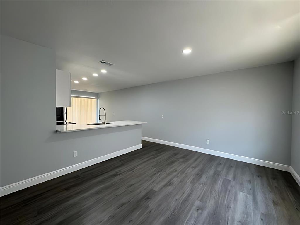 A room with gray walls, dark wood-look flooring, and a kitchen peninsula with white countertops — 442 S HILL AVENUE, DELAND, FL