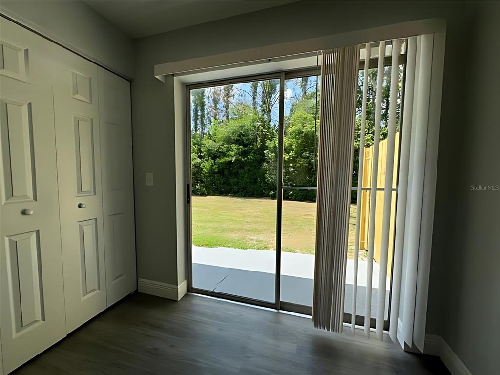 A room with gray wood-look flooring, white closet doors, and a sliding glass door to outdoors — 442 S HILL AVENUE, DELAND, FL