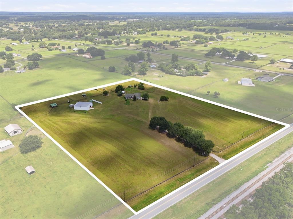 An aerial view shows a house and outbuilding on a large, fenced rural lot — 11748 NE JACKSONVILLE ROAD, ANTHONY, FL