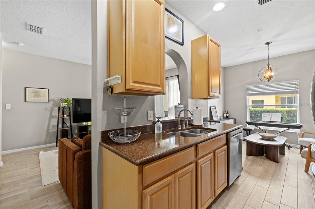 A kitchen with wood cabinets and brown countertops overlooks a living area and dining space — 723 MAROTTA LOOP, OCOEE, FL