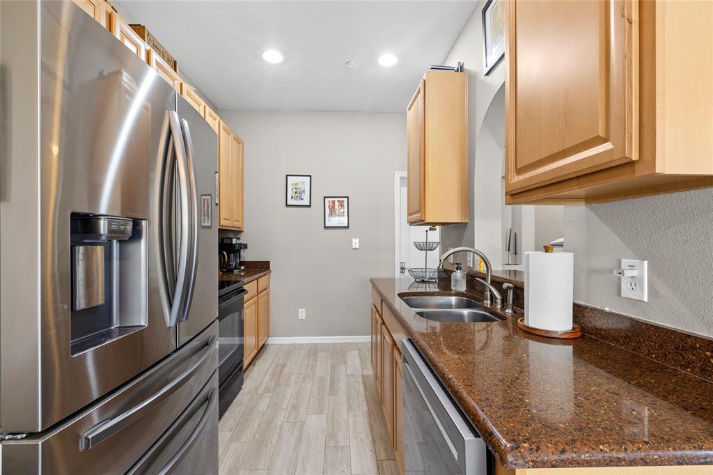 A kitchen features stainless steel appliances, wood cabinets, and dark granite countertops — 723 MAROTTA LOOP, OCOEE, FL