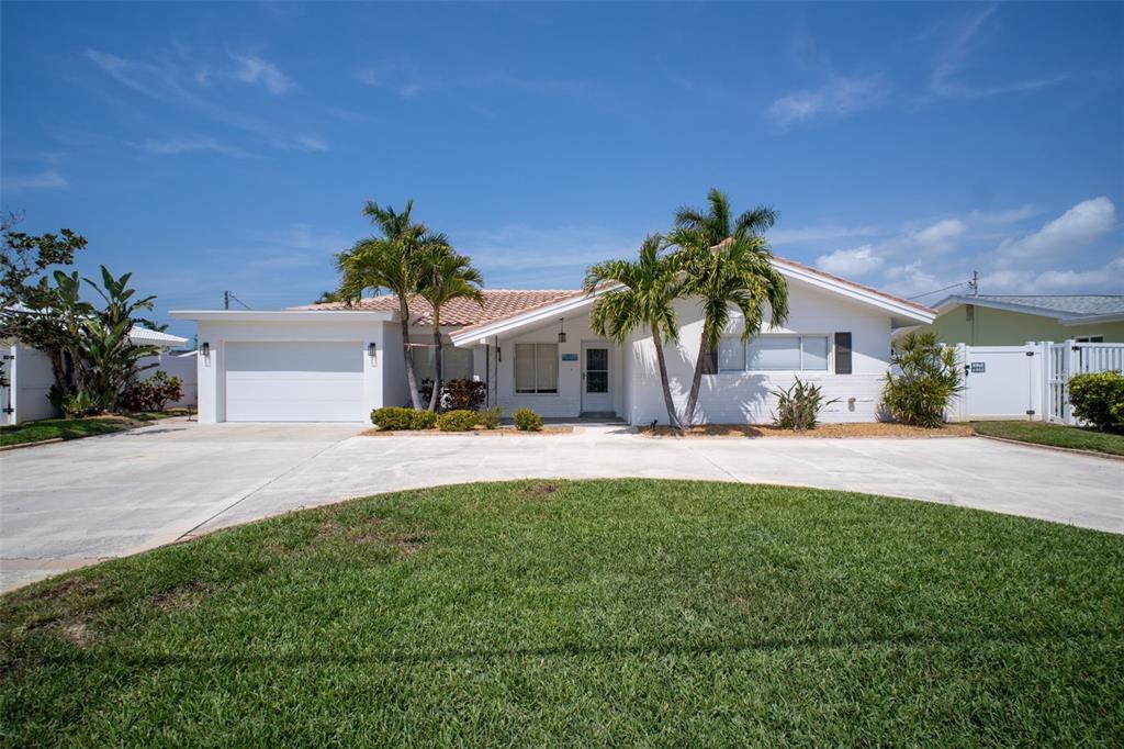 A white single-story house with a covered entryway, palm trees, and a concrete driveway — 2220 E VINA DEL MAR BOULEVARD, ST PETE BEACH, FL