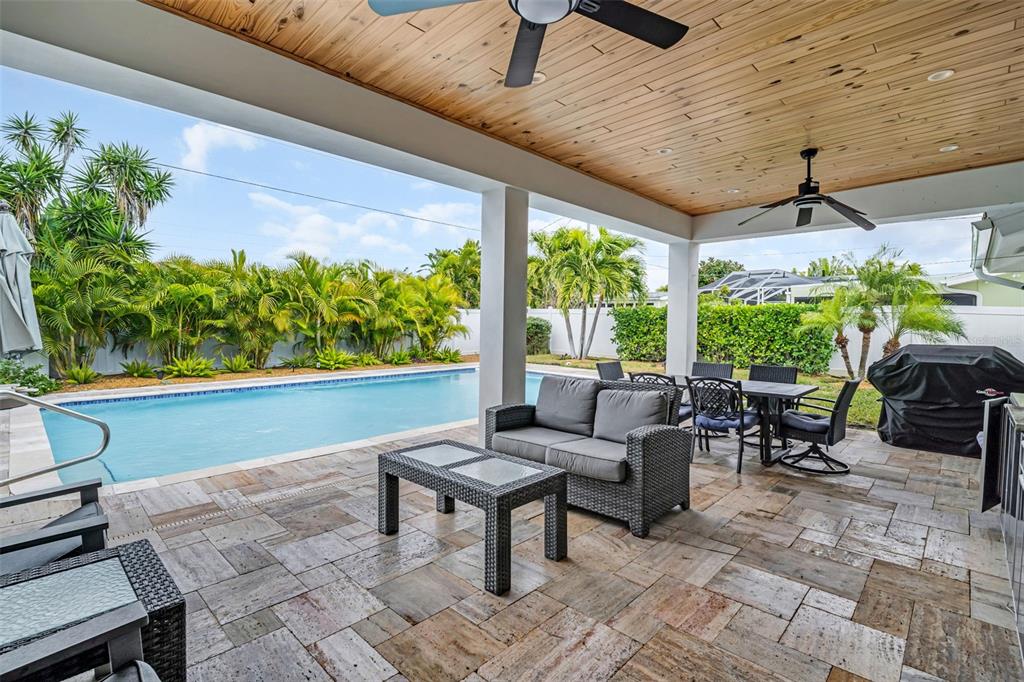 A covered outdoor patio features a wood-paneled ceiling, stone flooring, and a swimming pool — 2220 E VINA DEL MAR BOULEVARD, ST PETE BEACH, FL
