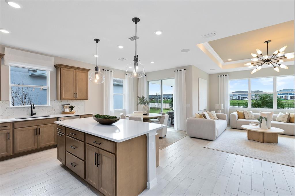 An open-concept kitchen and living area features light wood cabinetry, white countertops, and tile flooring — 2639 CLEAR NIGHT AVENUE, KISSIMMEE, FL