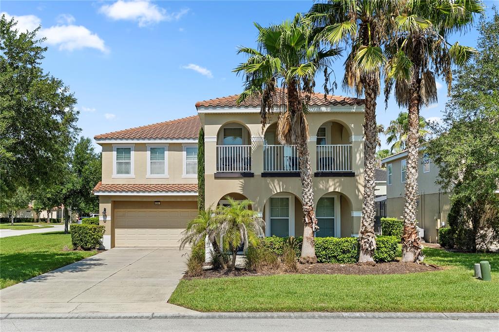 A two-story stucco house with a tile roof, arched balconies, and a two-car garage — 4200 OAKTREE DRIVE, DAVENPORT, FL