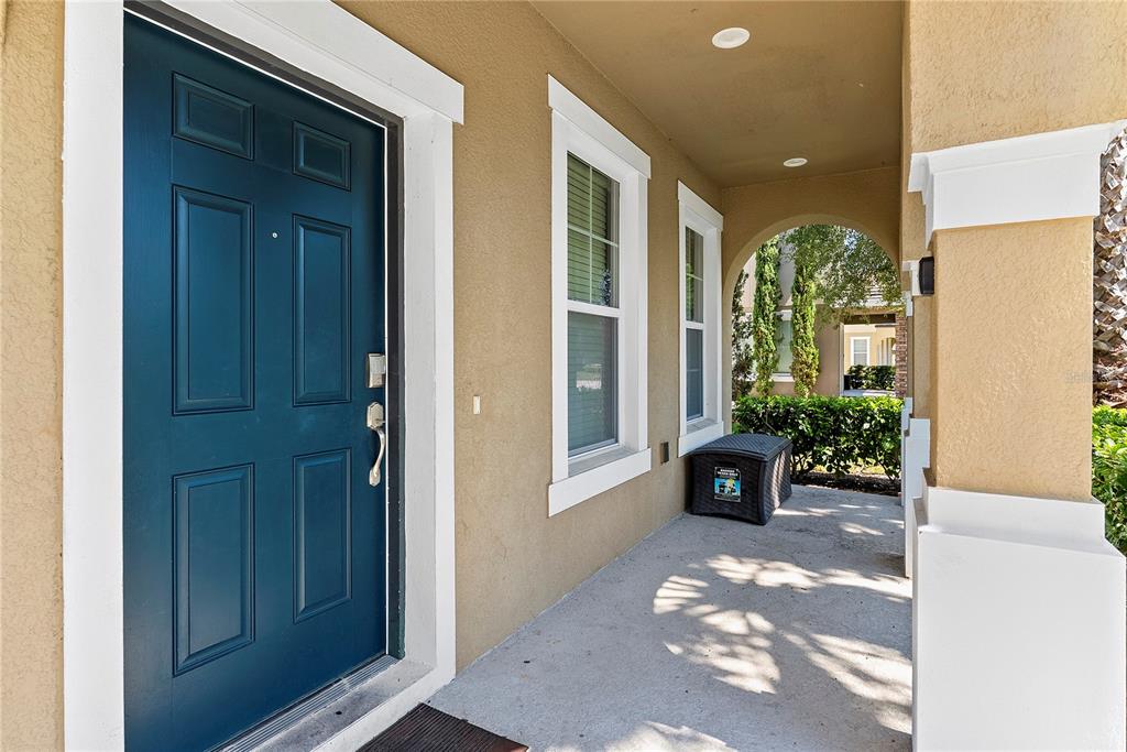 A covered front porch features a dark blue door, beige walls, and white trim — 4200 OAKTREE DRIVE, DAVENPORT, FL