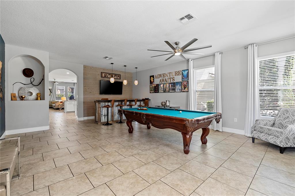 A game room features a pool table, a bar with stools, and tile flooring — 4200 OAKTREE DRIVE, DAVENPORT, FL