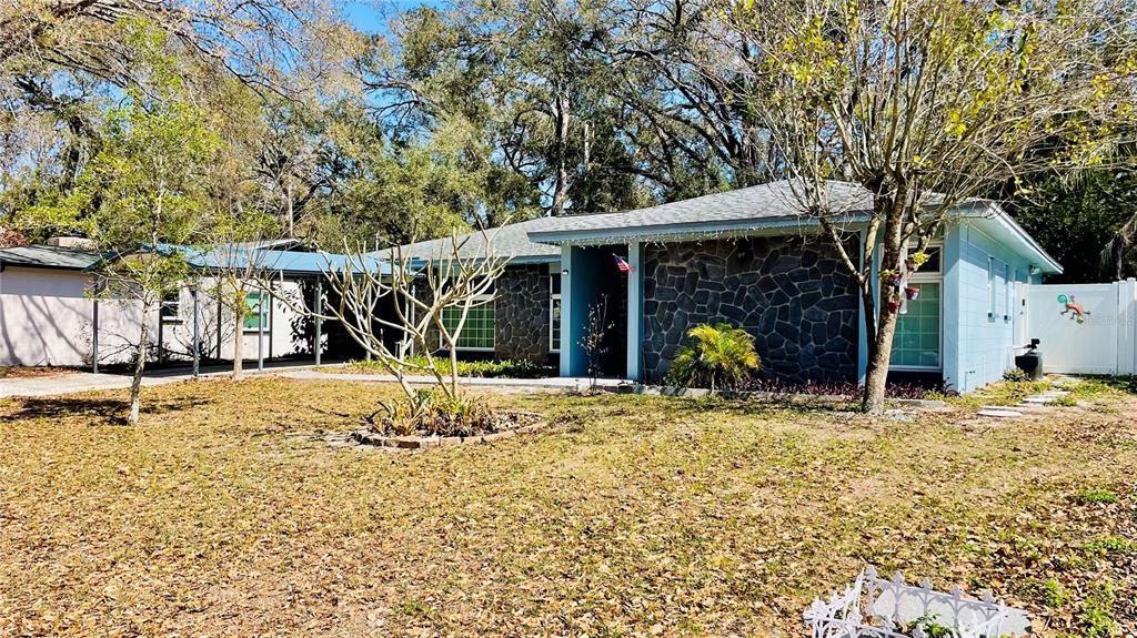 A single-story house with a stone facade, blue siding, and a metal carport — 14809 TULIP DRIVE, TAMPA, FL