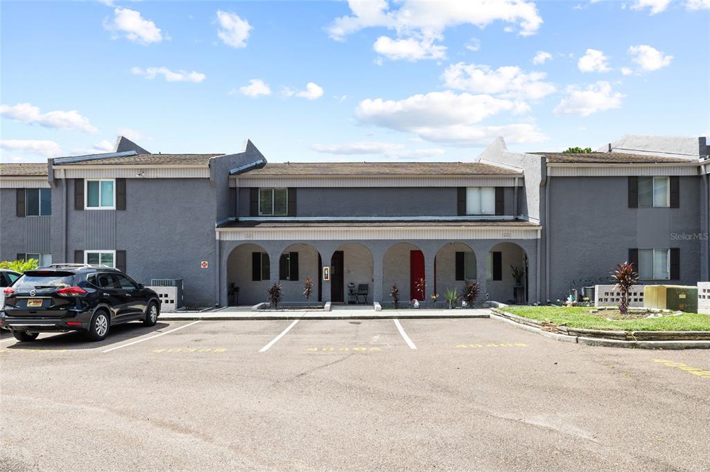 A two-story gray townhouse exterior features arched entryways and a parking lot in front — 4038 CORTEZ DRIVE UNIT B, TAMPA, FL