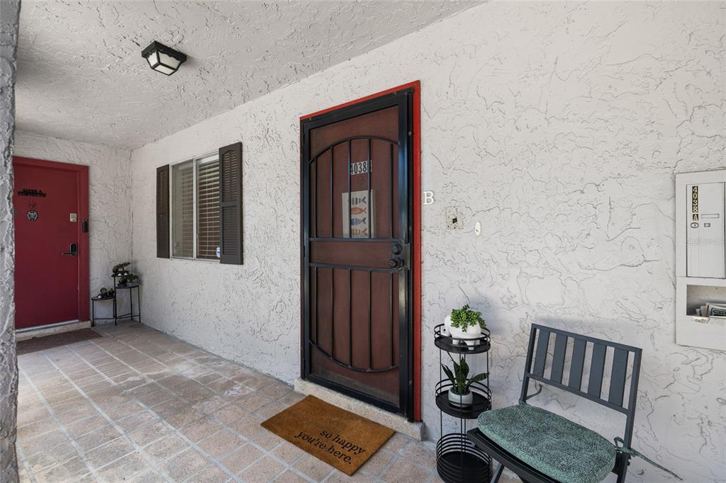 An exterior view of a building entrance with two doors, a tiled porch, and furniture — 4038 CORTEZ DRIVE UNIT B, TAMPA, FL